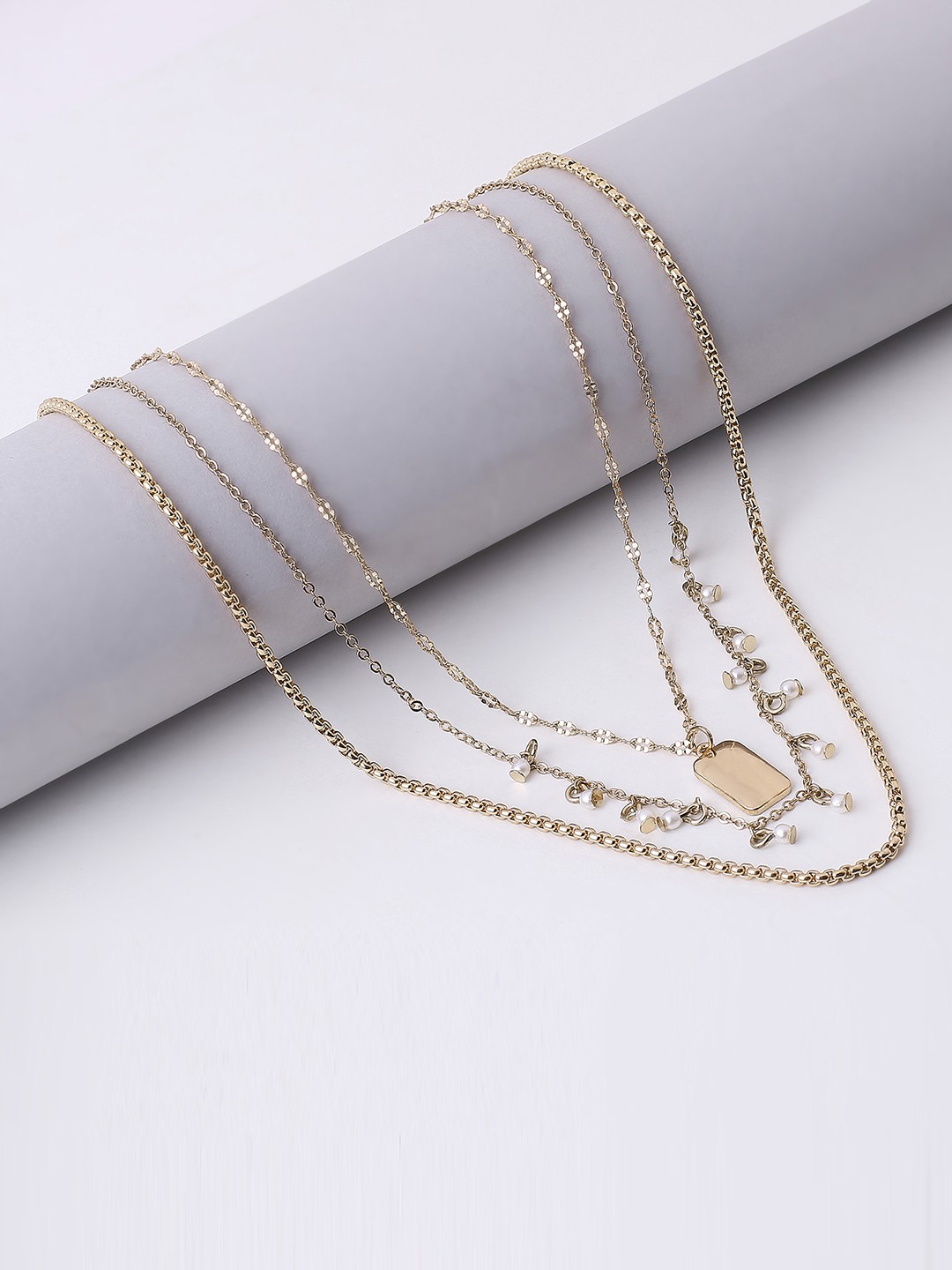 Gold toned 4 layered necklace with coin, rectangular pendant and pearls.